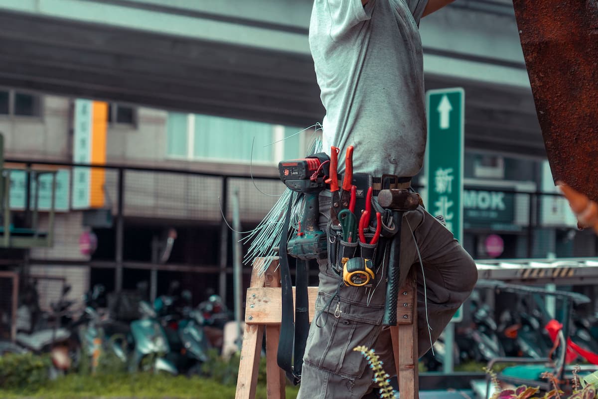 Appliance repair technician working on a kitchen appliance with a tool bag